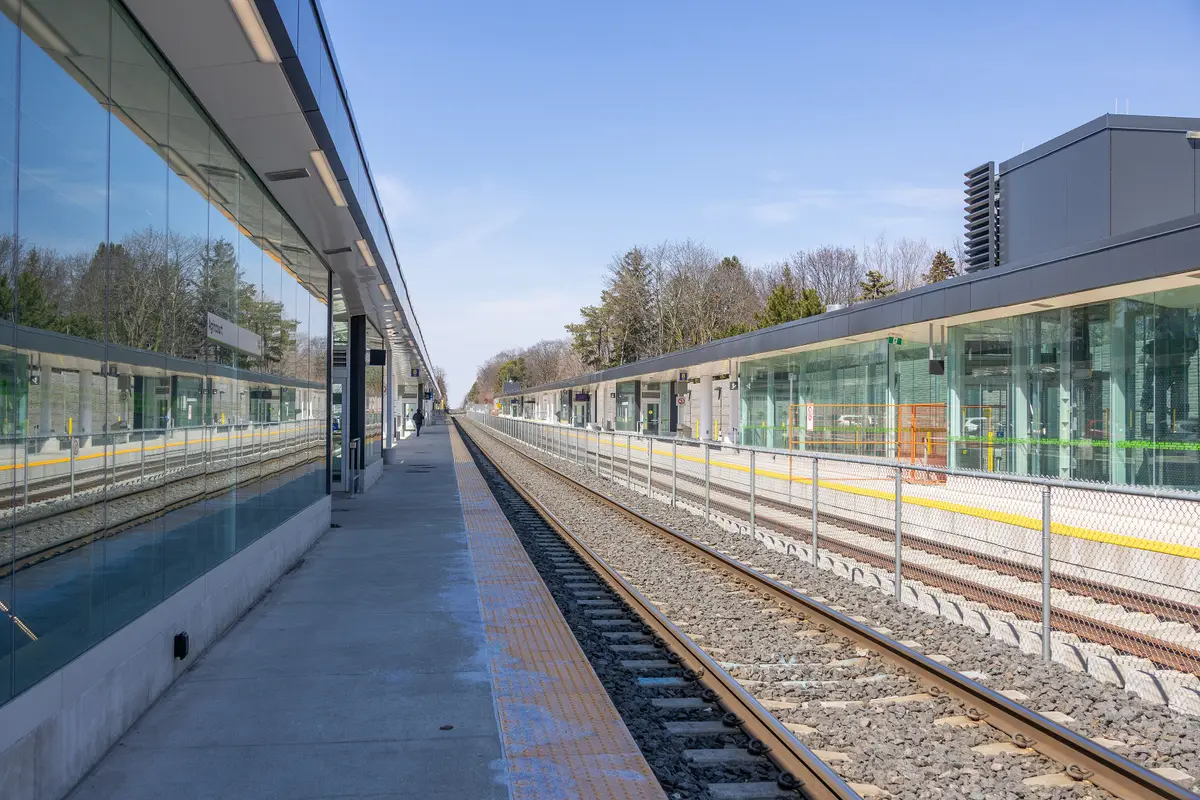 A glass-walled GO platform at Agincourt GO Station, with tracks running alongside under a clear sky
