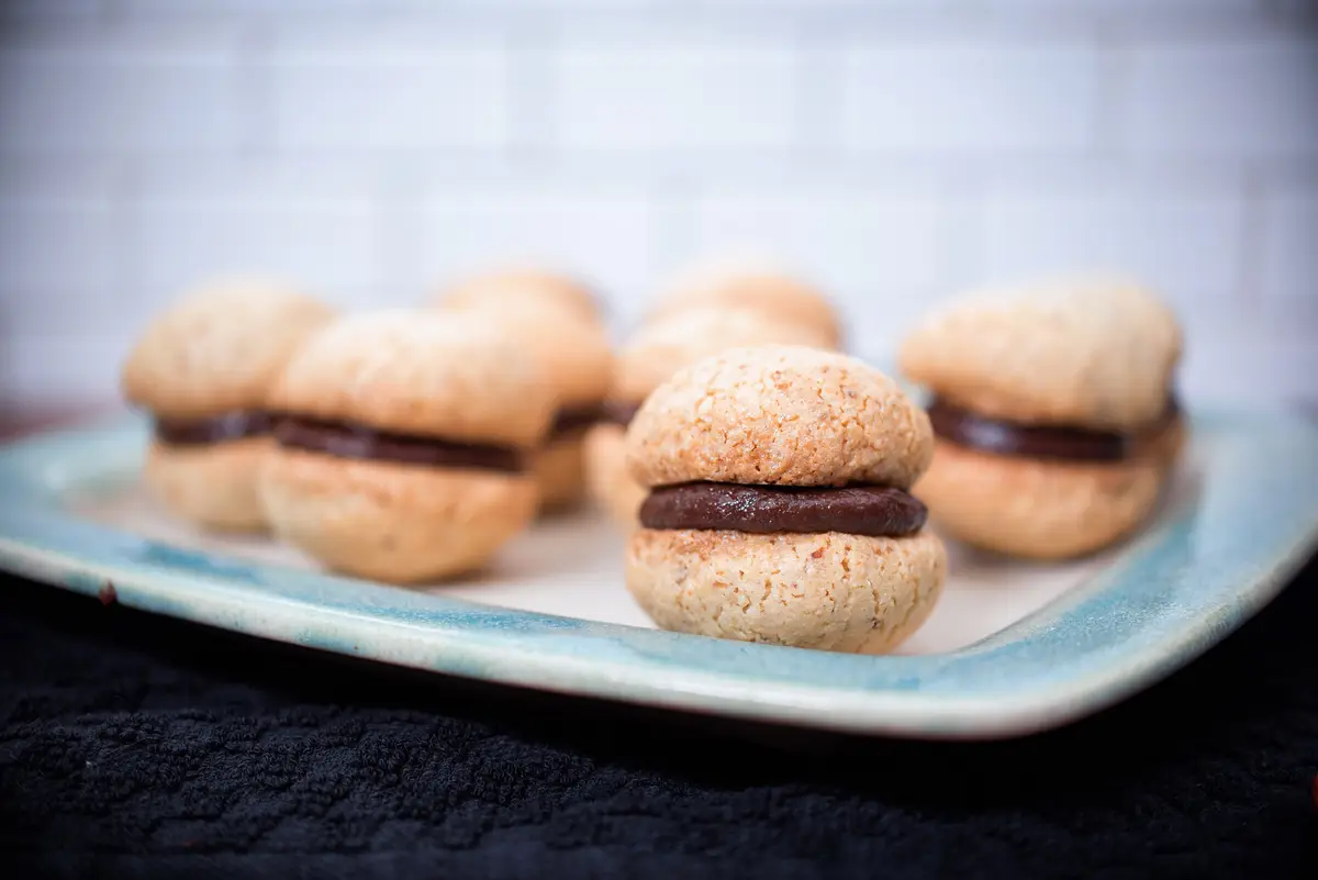 Round sandwich cookies with a chocolate filling on a blue-rimmed ceramic plate