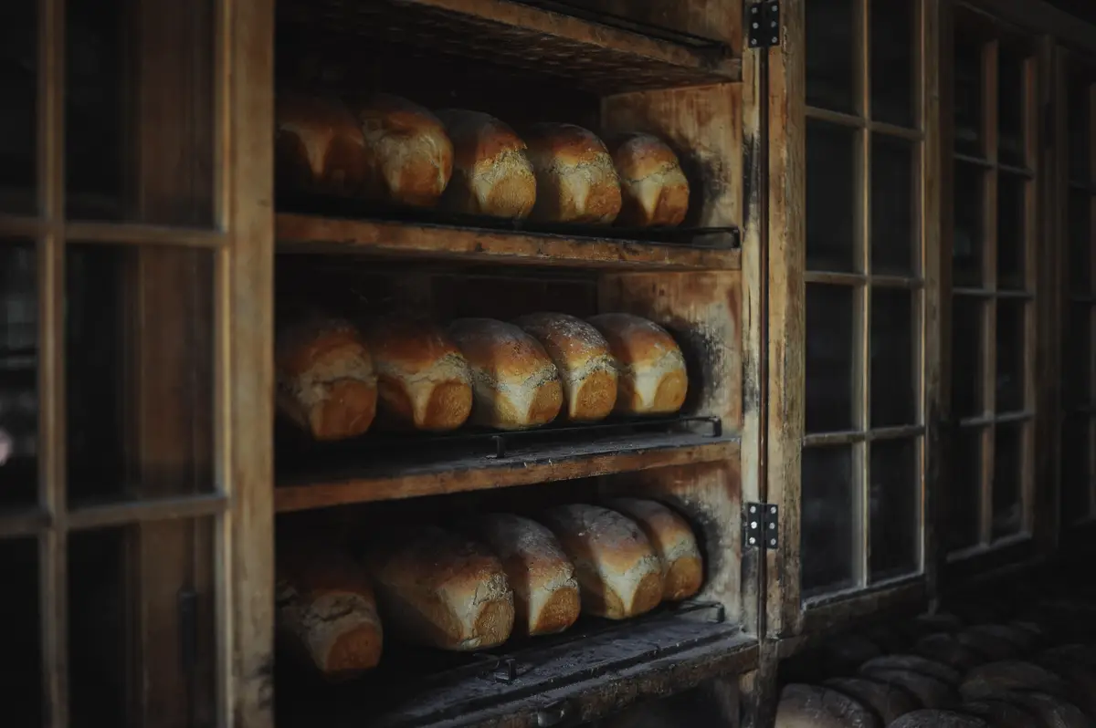 Golden loaves on wooden racks inside a bakery cabinet