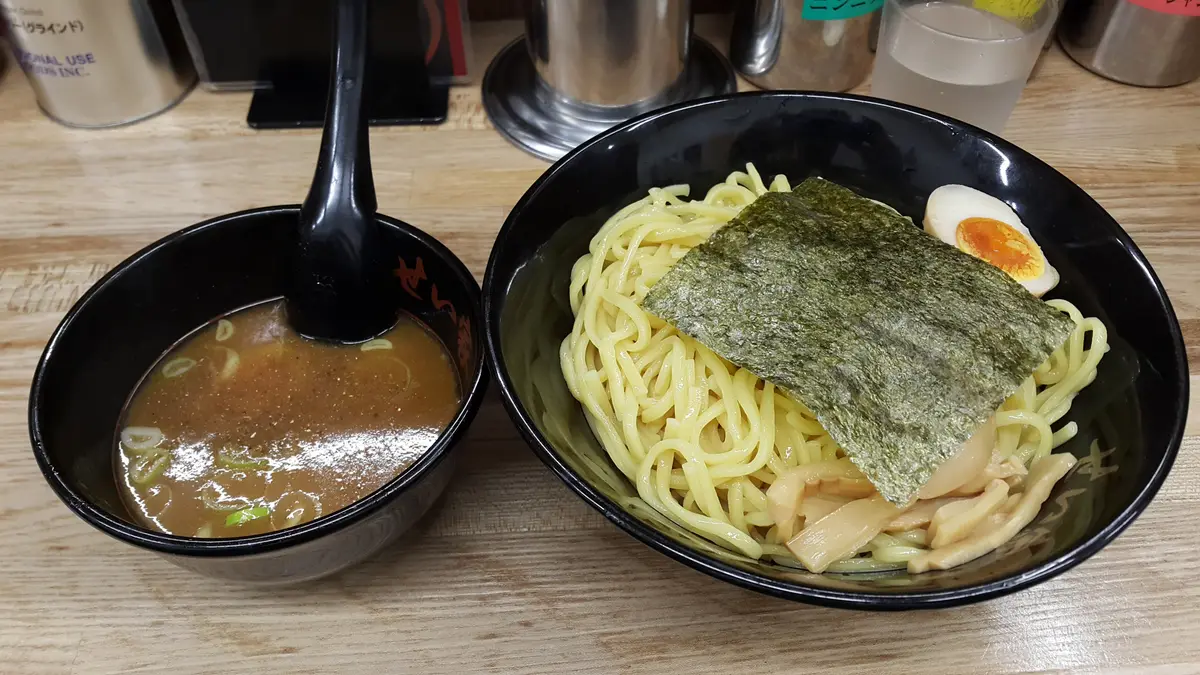 A bowl of tsukemen dipping ramen: noodles topped with nori and half a soft-boiled egg, beside a small bowl of dipping broth.