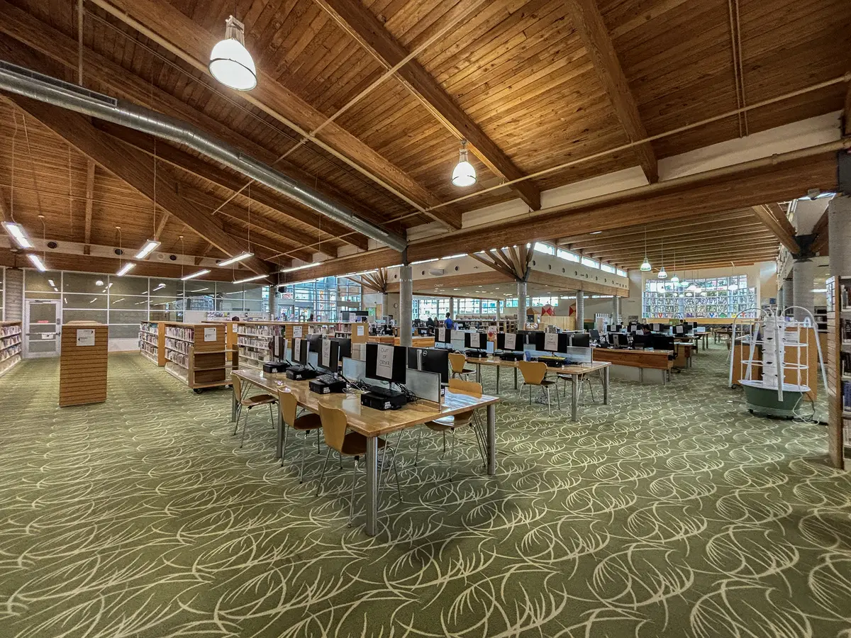 The bright, wood-ceilinged interior of the Malvern branch of Toronto Public Library, with rows of tables and computers
