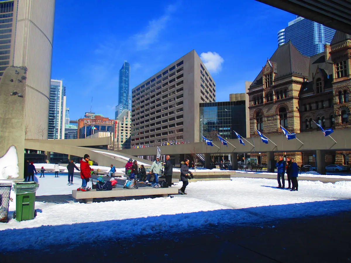 Skaters on the Nathan Phillips Square rink, with the Old City Hall tower and office towers behind