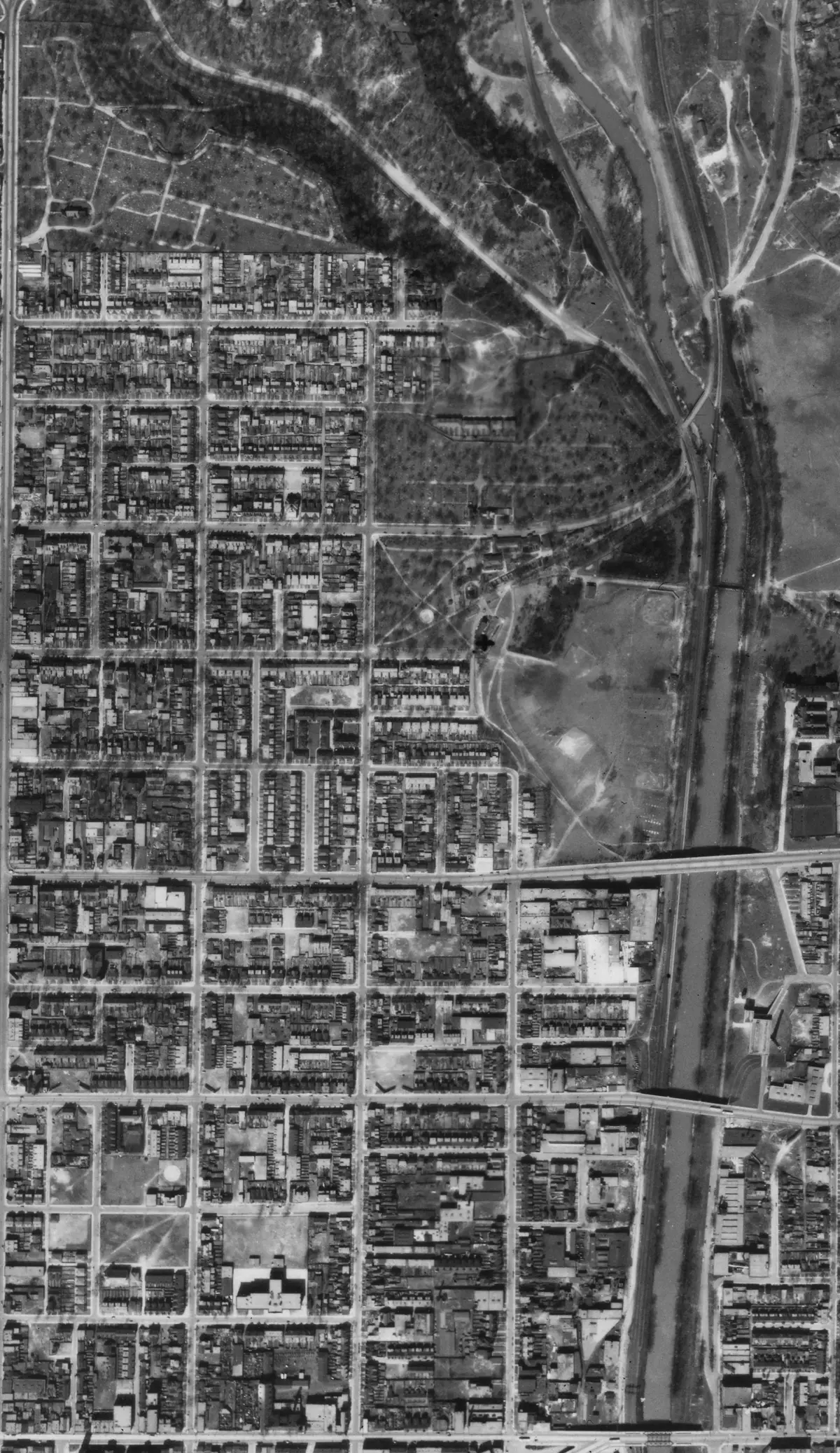 Black-and-white aerial photograph of a dense grid of narrow streets and rows of houses