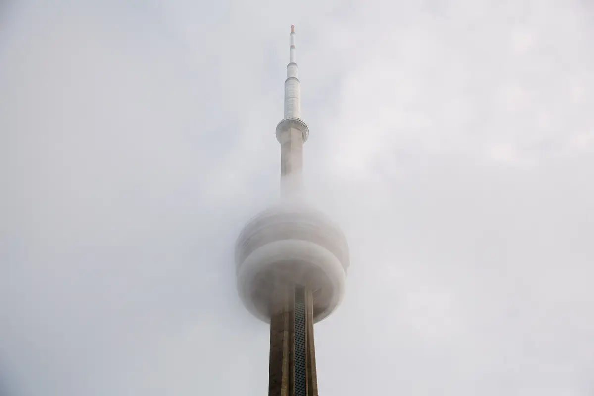 The CN Tower's observation pod and antenna disappearing into low cloud