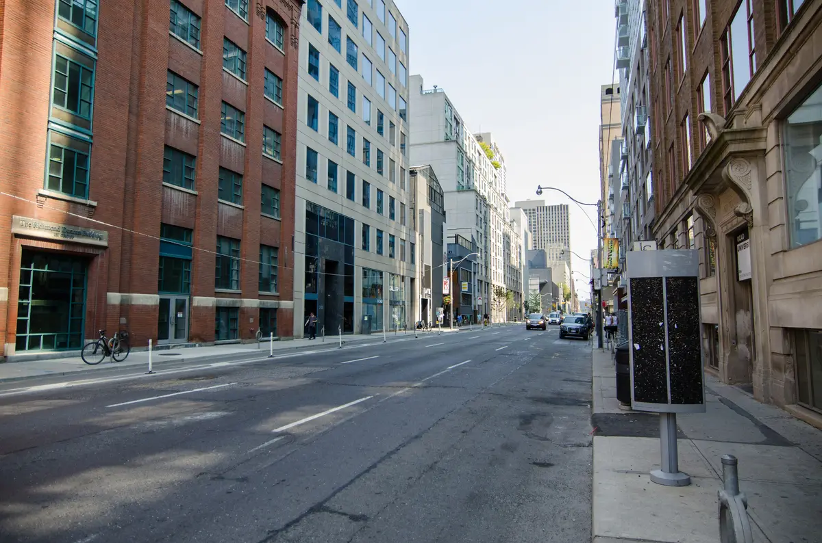 A downtown street lined with red-brick and glass buildings, with a parked bicycle on the left