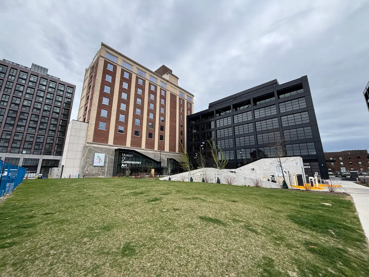 Brick building with a glass entrance and the Museum of Contemporary Art Toronto sign, with a lawn in front.