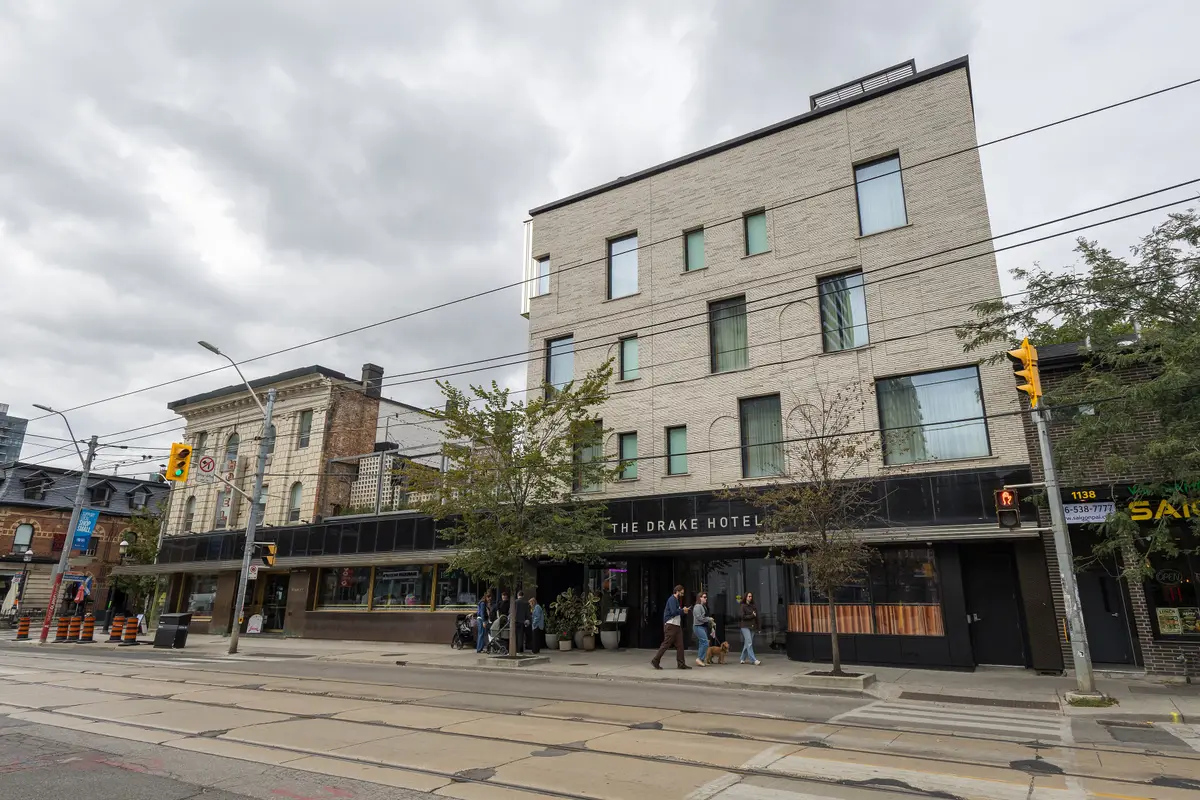 The Drake Hotel's brick and glass front on Queen Street West, with streetcar tracks in the foreground