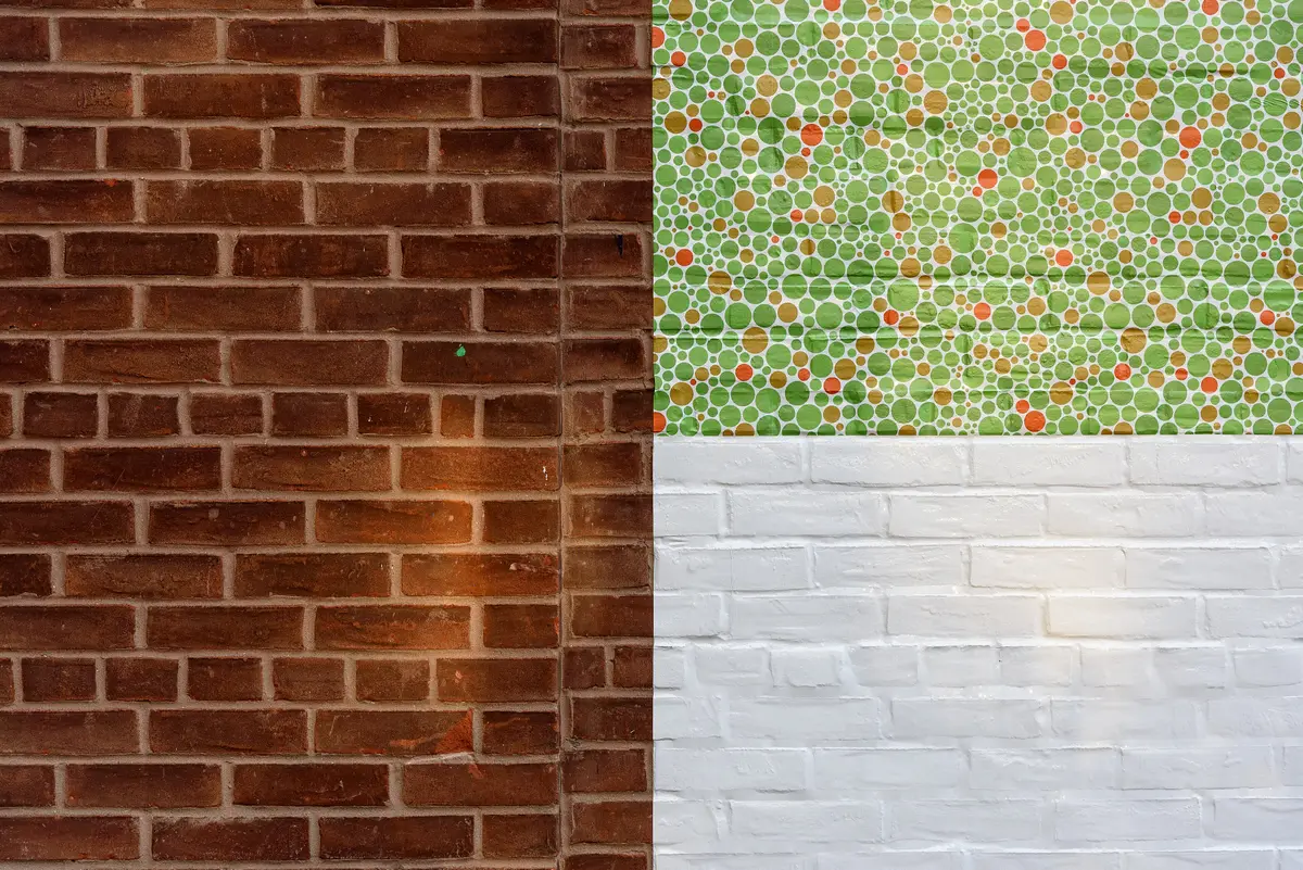 A brick wall in the Toronto Distillery District with a panel of green, orange and gold dots above painted white brick