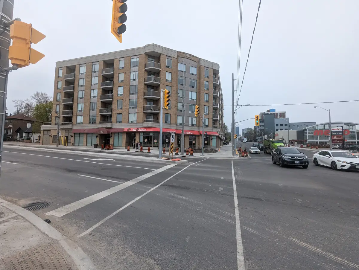 Bayview Avenue at Eglinton Avenue East in Leaside, with a brick apartment building and storefronts at the corner