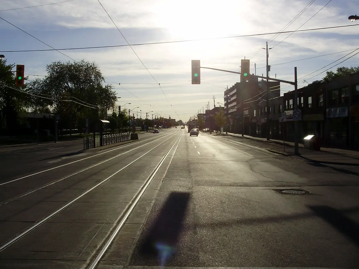 Lake Shore Boulevard West in Long Branch at low sun, with streetcar tracks in the road and low buildings along the north side