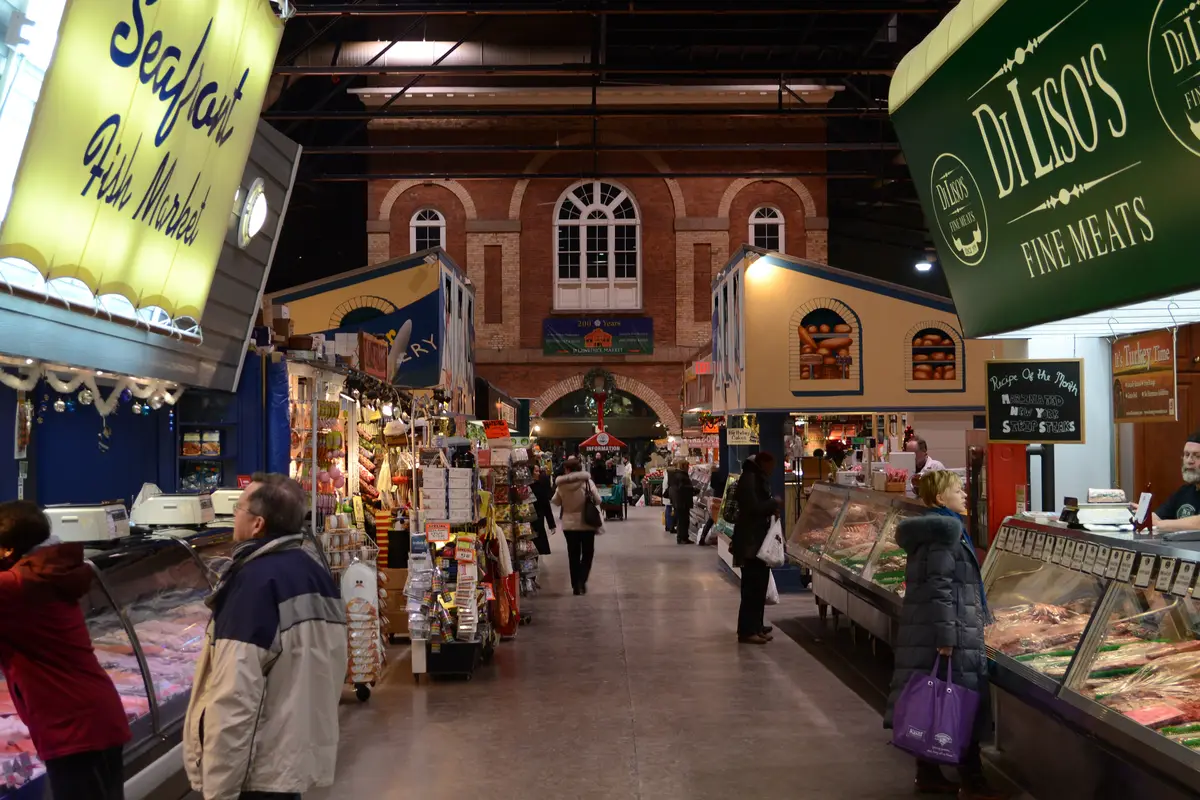 Shoppers walking an aisle between seafood and meat counters in a brick market hall