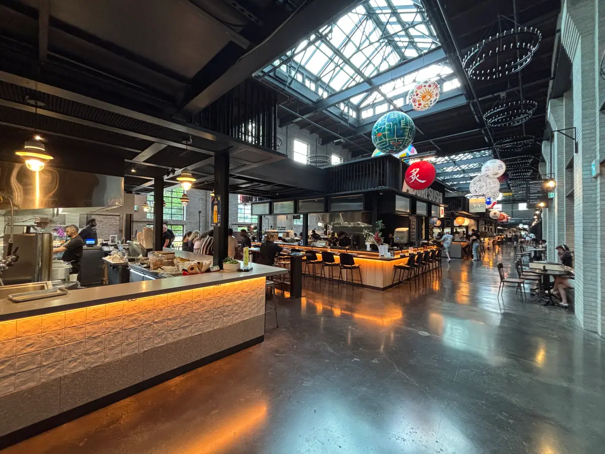 Inside Waterworks Food Hall: a lit counter and open seating under a skylit roof with hanging decorations