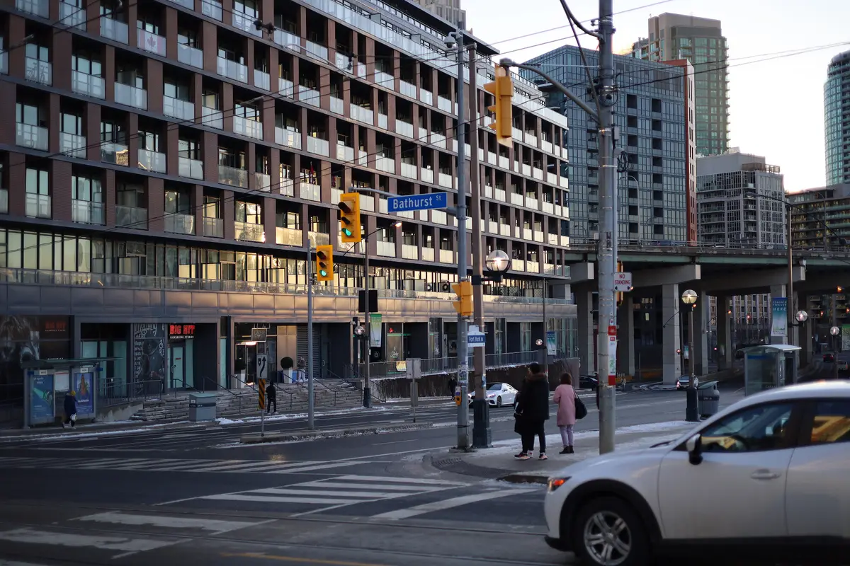 The corner of Bathurst Street and Fort York Boulevard in winter, with street signs, traffic signals, a crosswalk and condo buildings behind