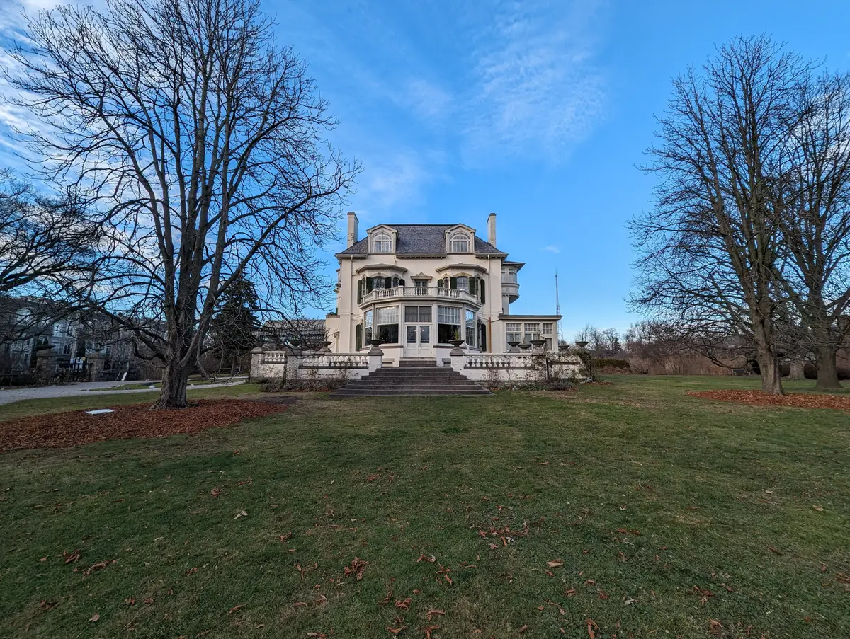 The back of Spadina House seen across a lawn and bare trees under a blue December sky