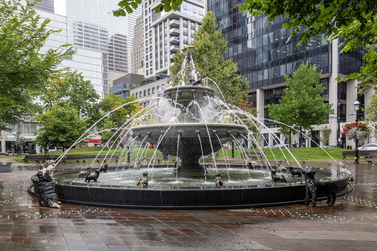The tiered fountain in Berczy Park, with dark dog statues around its basin and downtown towers behind