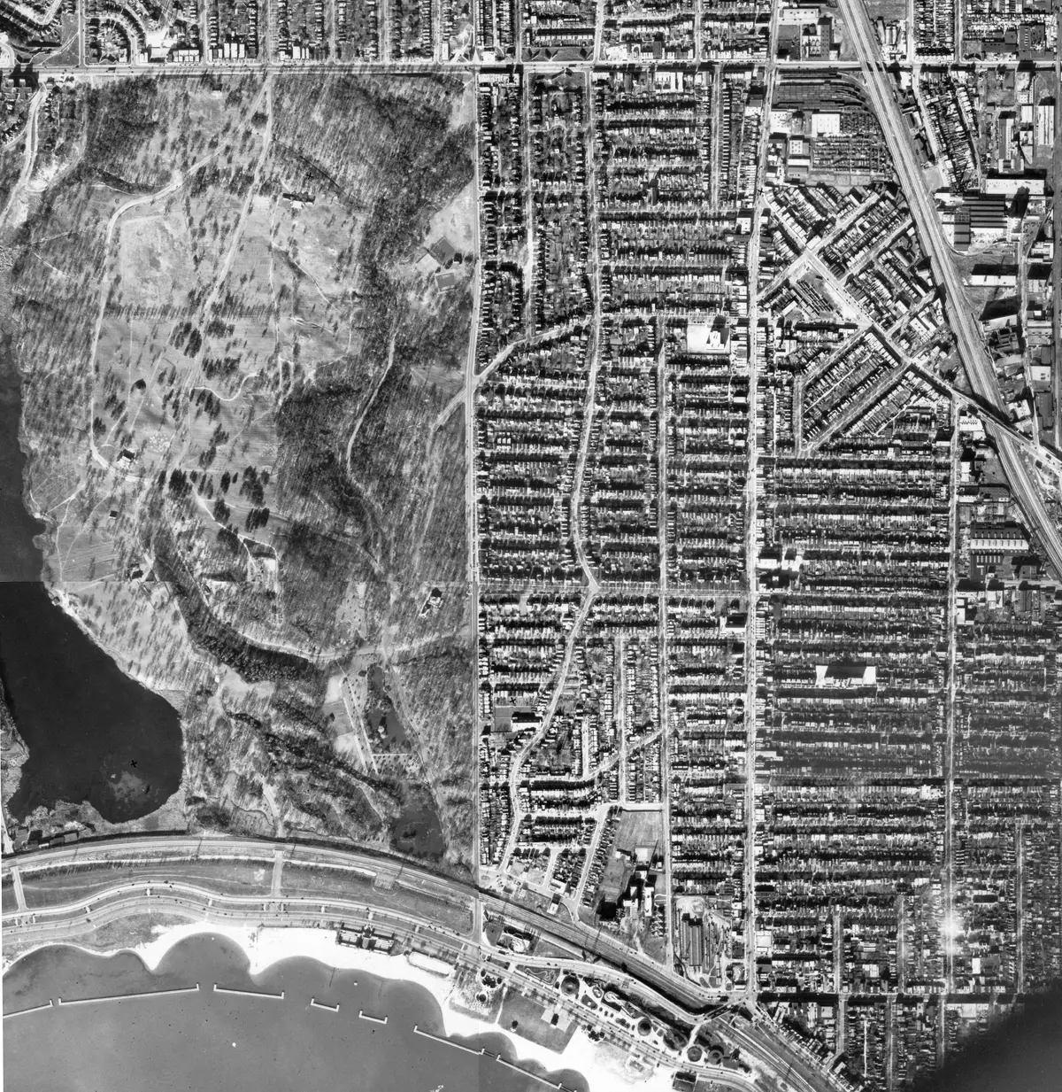 Black-and-white composite aerial photograph from 1937 of the Sunnyside and High Park area: wooded parkland on the left, a dense grid of residential streets to its right, and the lakeshore along the bottom