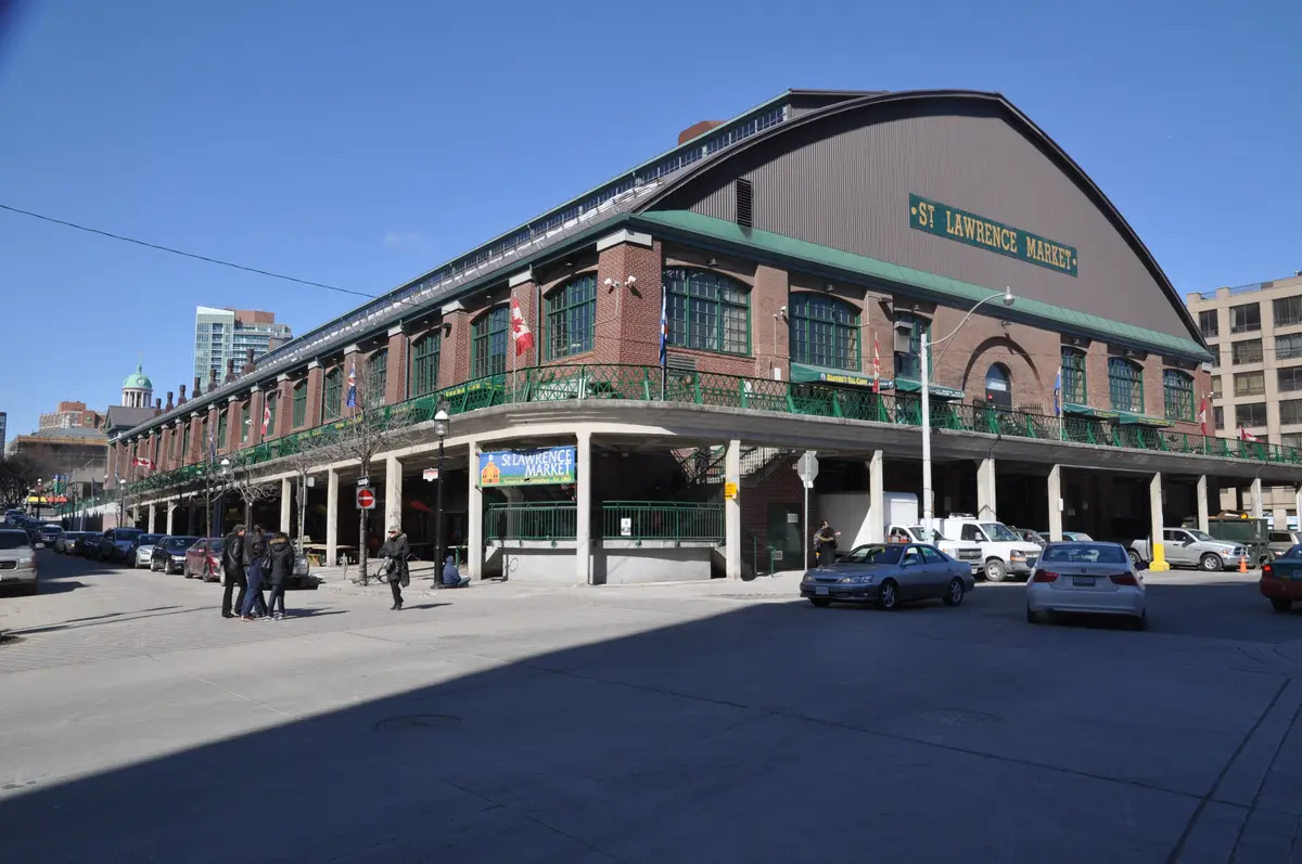 The arched St. Lawrence Market building on a sunny day, with green-trimmed railings on its upper level and the market sign