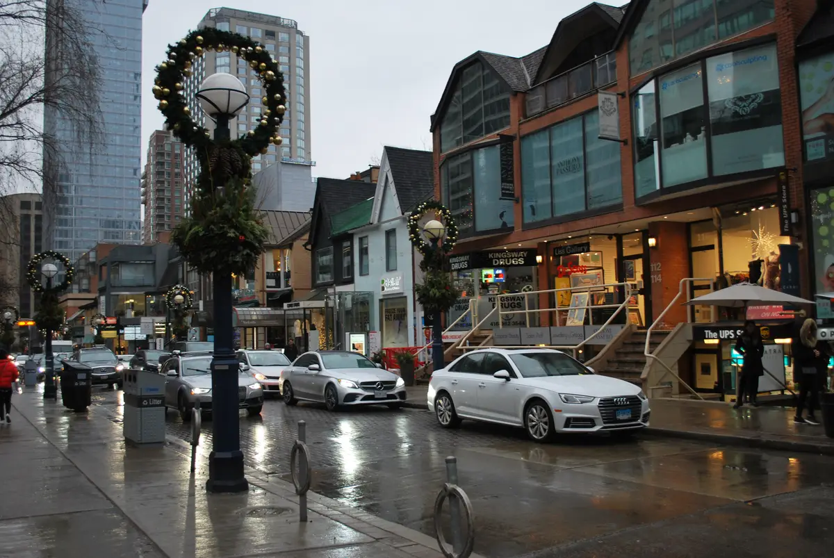 A wreath wrapped around a lamp post on a wet Cumberland Street in Yorkville, with shops behind