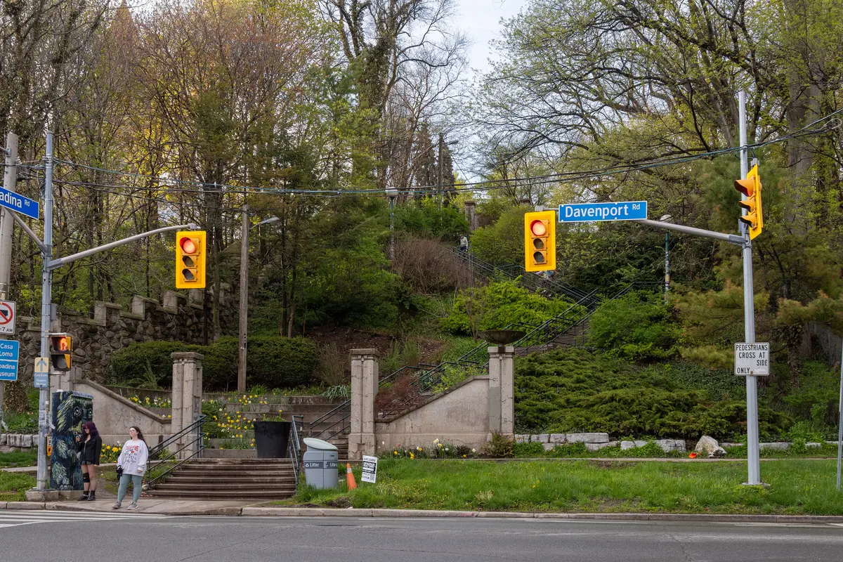 The Baldwin Steps climbing a green hillside from Davenport Road, beside traffic lights and a blue street sign