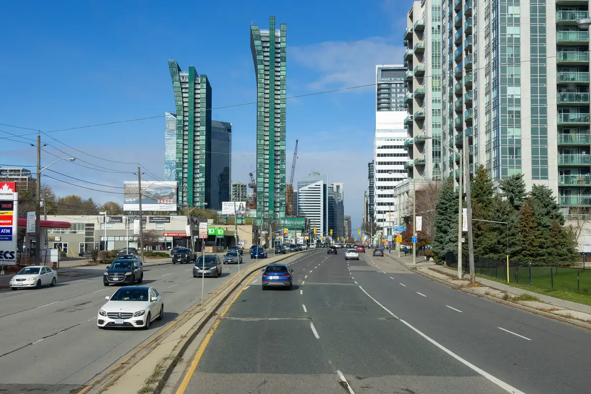 A wide, straight stretch of Yonge Street in North York under a bright blue sky, with condo towers and traffic