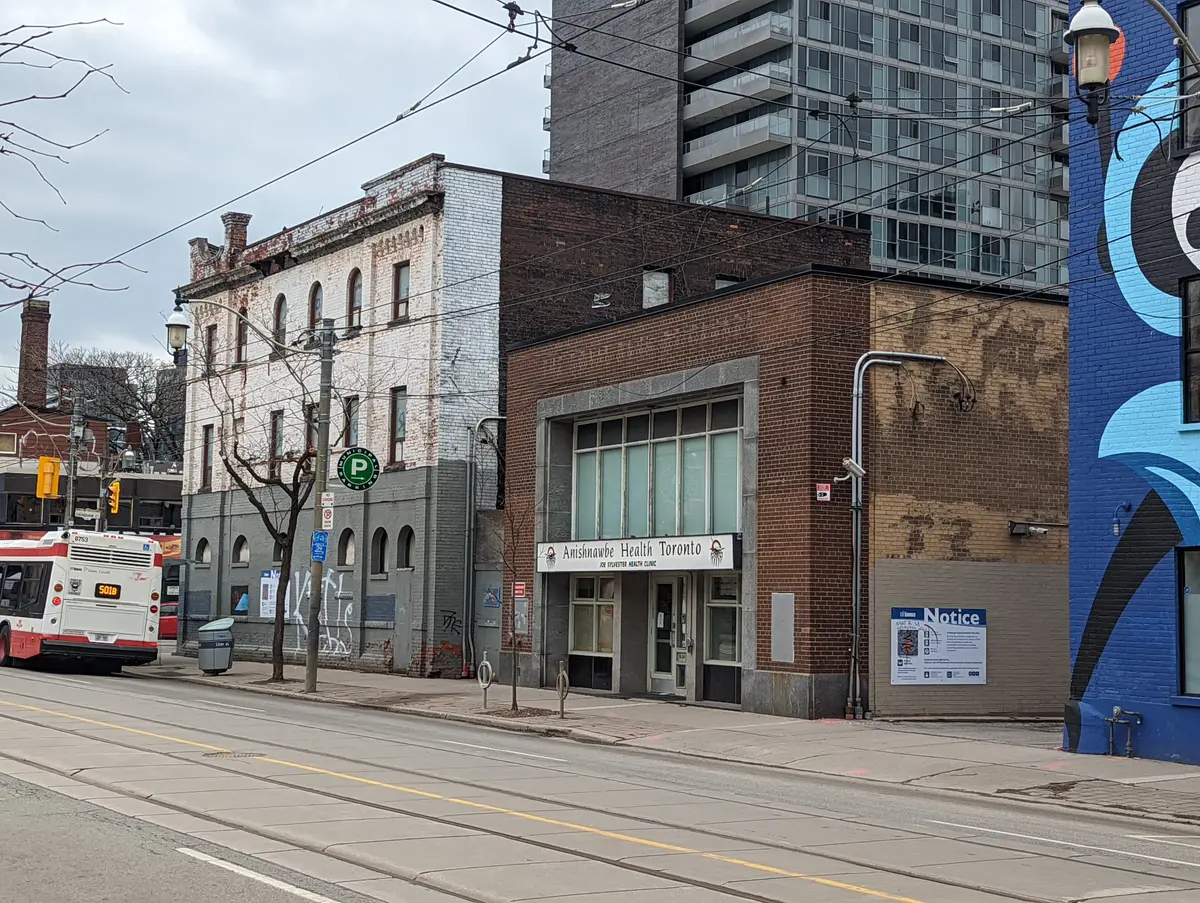 A street view of Queen Street East, with a bus and a mural on a side wall