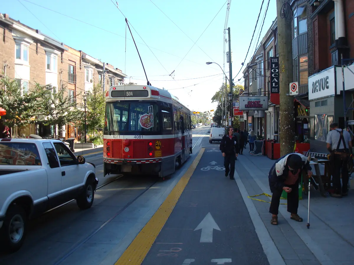 A streetcar at a Roncesvalles Avenue stop, with the Revue Cinema to the right