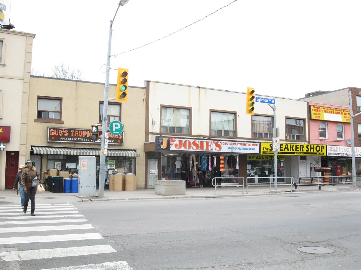 Shops and signs on Eglinton Avenue West at Oakwood Avenue on an overcast day