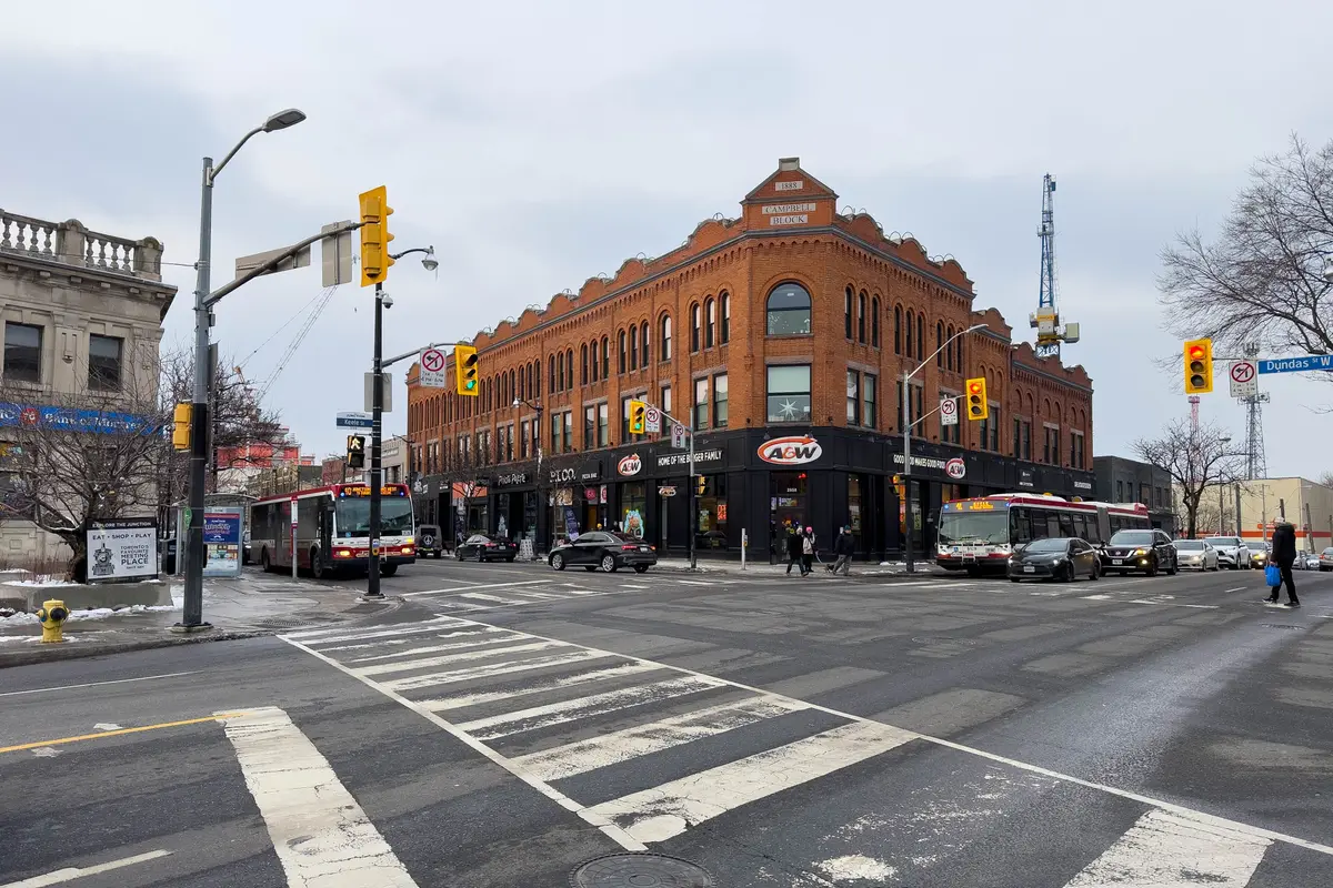 The corner of Dundas Street West and Keele Street in the Junction, with a red-brick corner block and a bus at the curb