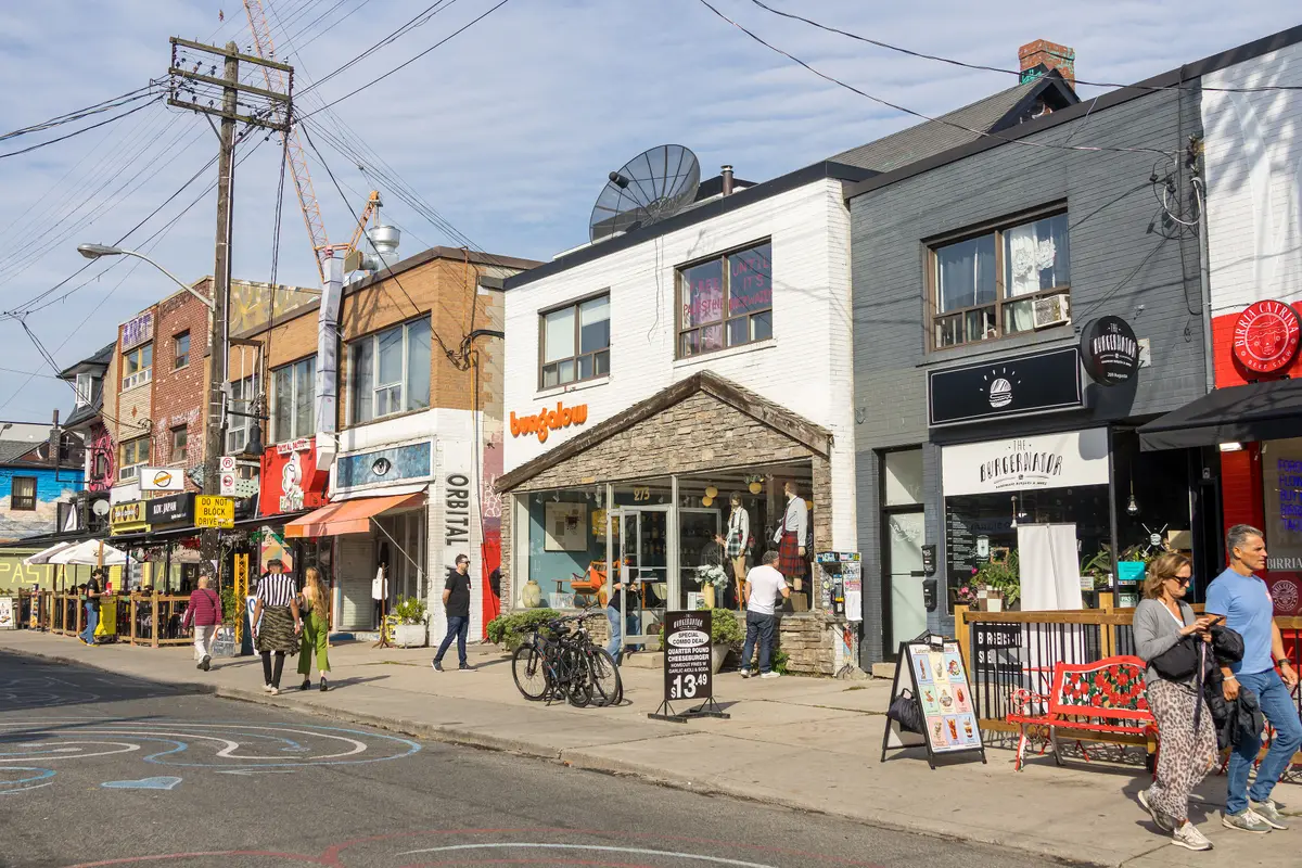 Shopfronts, patios and walkers along Augusta Avenue in Kensington Market on a sunny autumn day