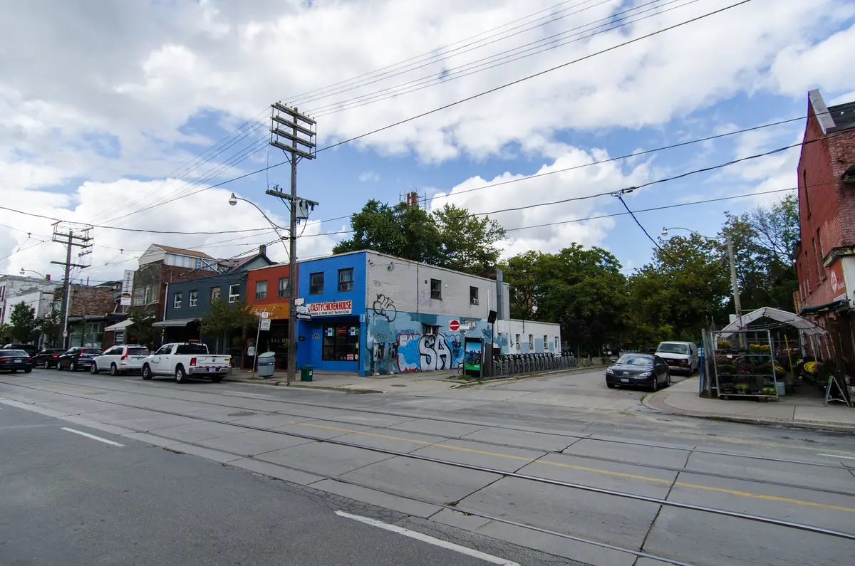Queen Street East at Boston Avenue in Leslieville, with low-rise shopfronts and streetcar wires