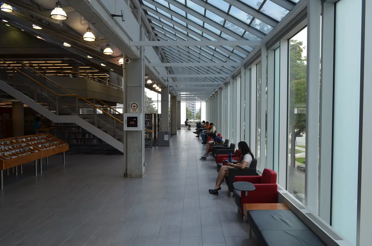 Glass-roofed corridor inside the Fairview branch, with people seated in red armchairs beside tall windows
