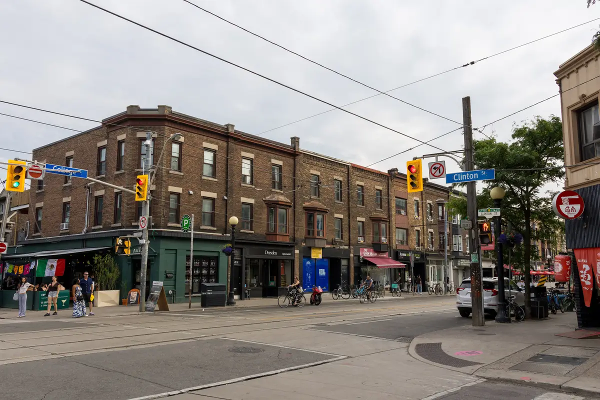 Brick shopfronts with awnings and bicycles on the corner of College Street and Clinton Street in Little Italy