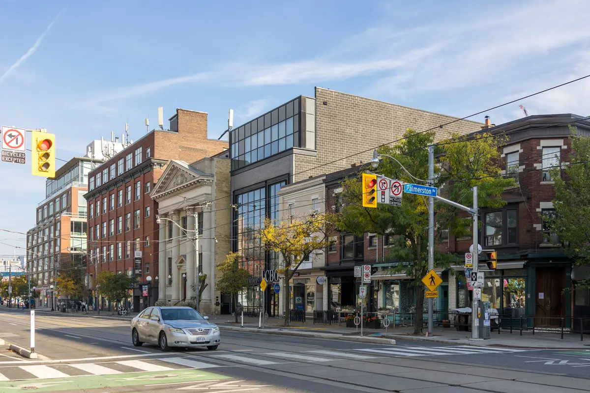 Brick buildings and autumn trees along the south side of College Street east of Palmerston Avenue