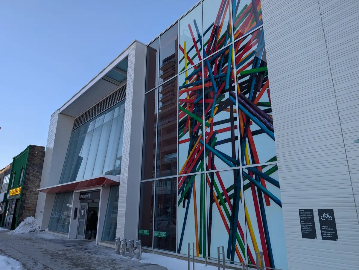 Colourful strip-pattern window art covering part of the glass front of Oakwood Station