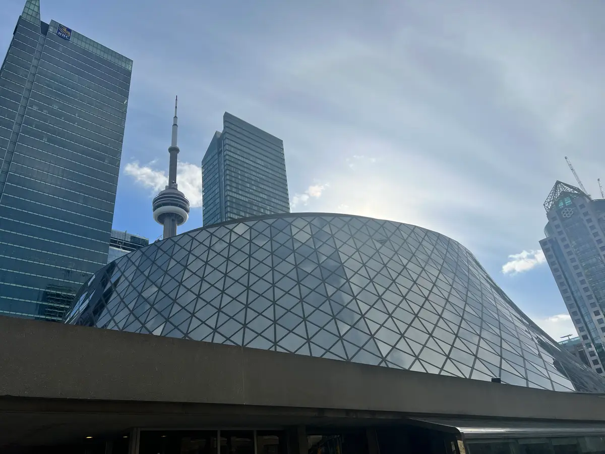 Roy Thomson Hall's curved, latticed glass roof, with the CN Tower and office towers behind it.