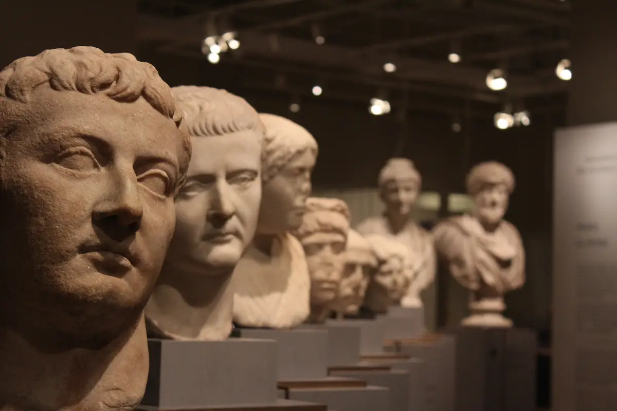 A row of Roman portrait busts on plinths, lit from above in a dim gallery