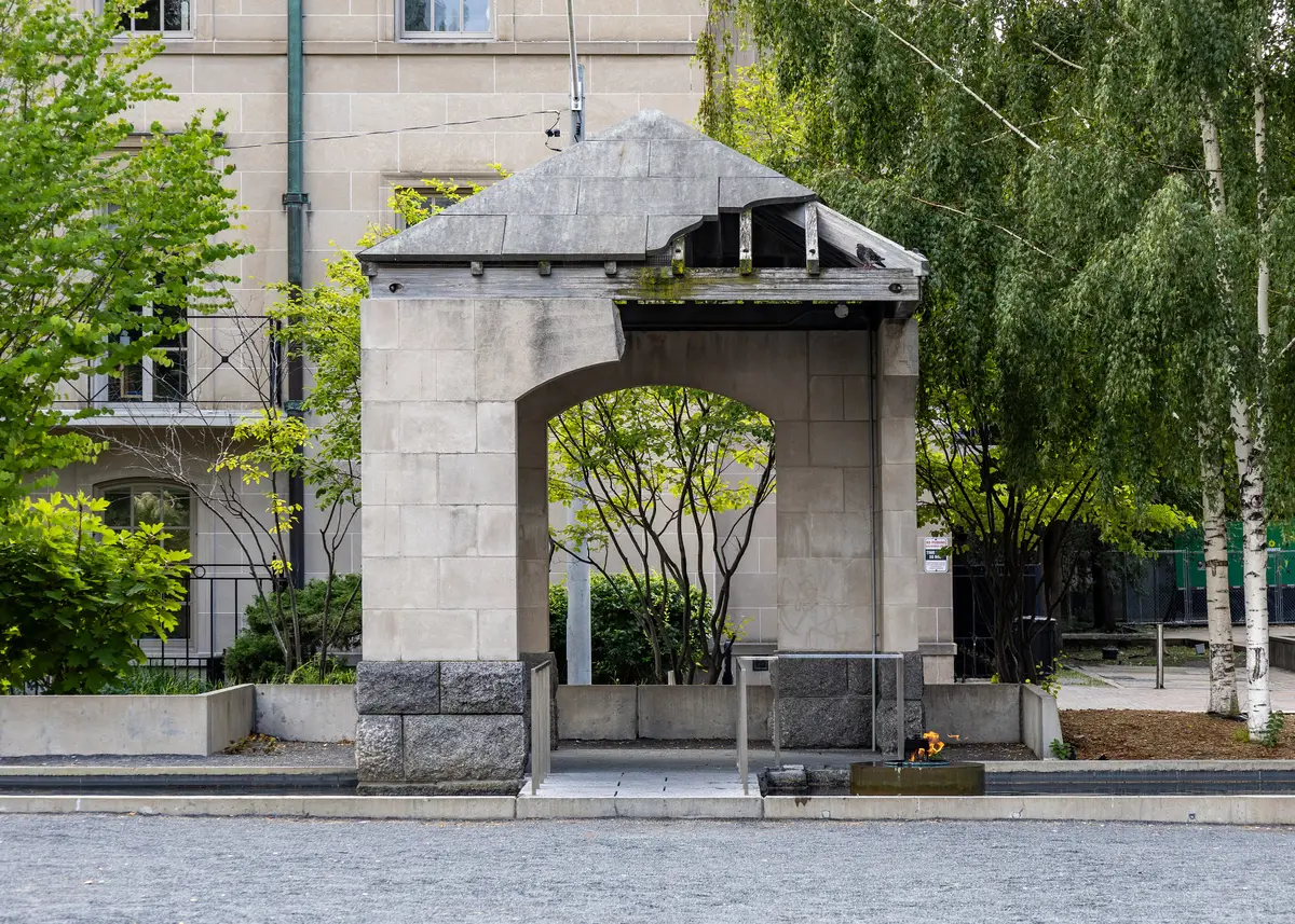 The stone arch of the Peace Garden with a paved walk and birch trees around it.