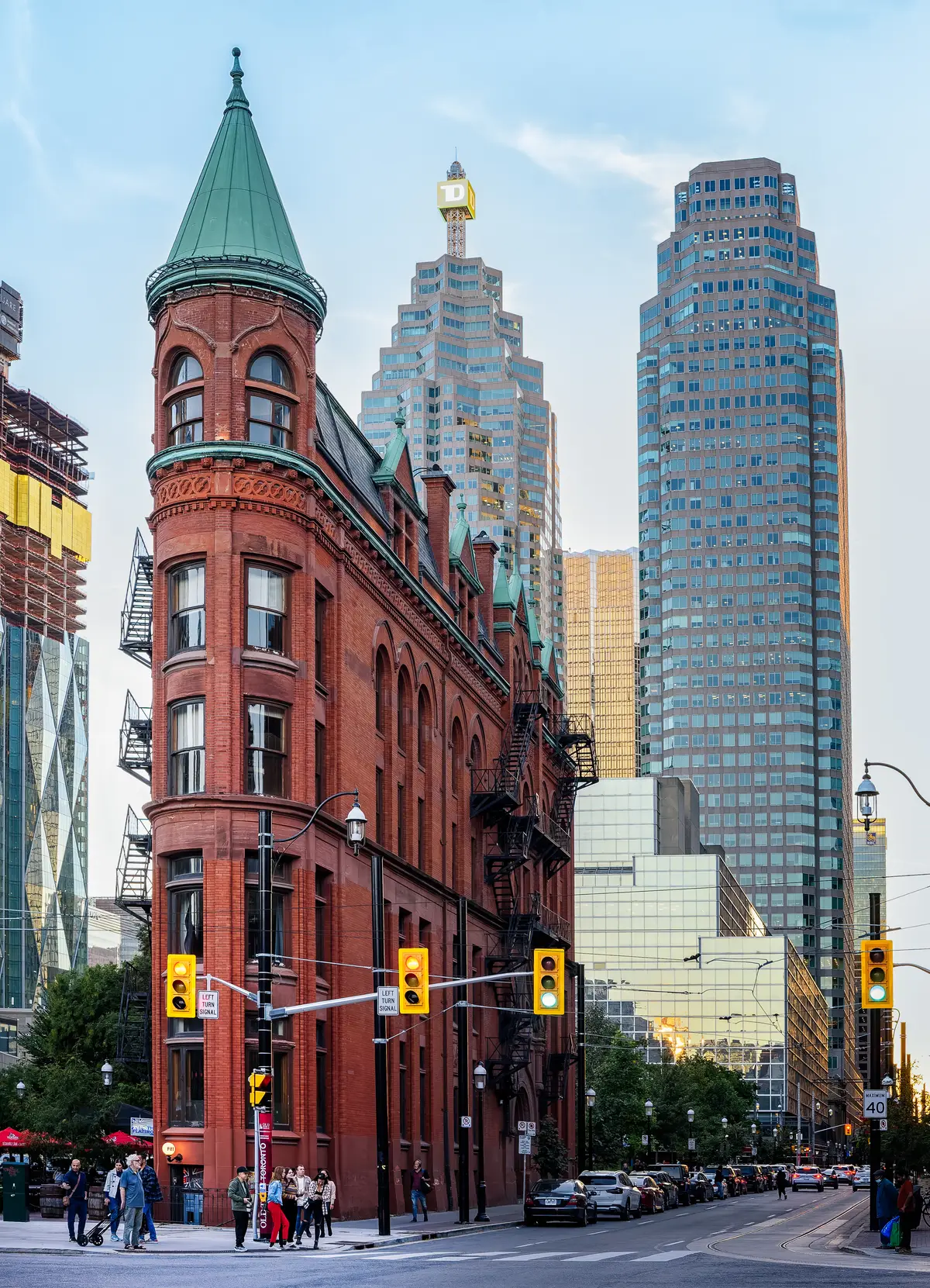 The red-brick Gooderham Building, its pointed wedge end topped with a green roof, on a city corner