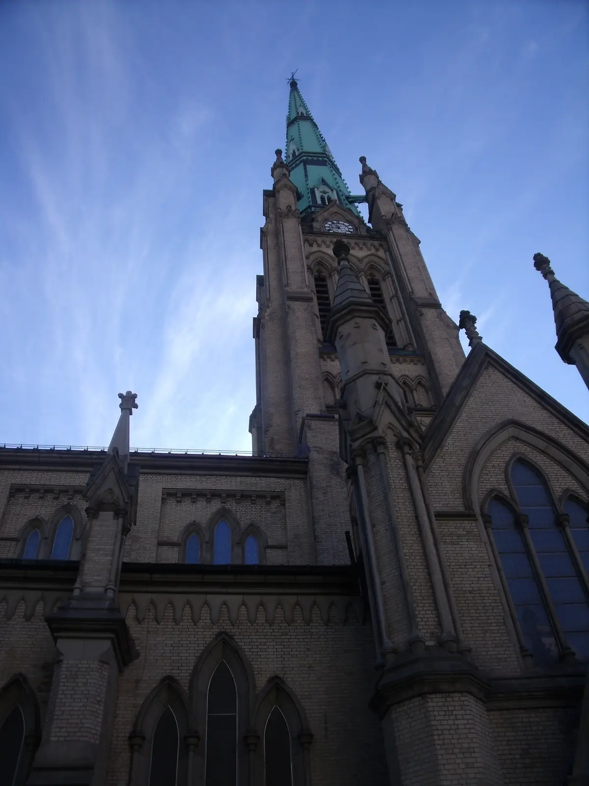 The tower and green-capped spire of St. James' Cathedral, photographed from below against a blue sky
