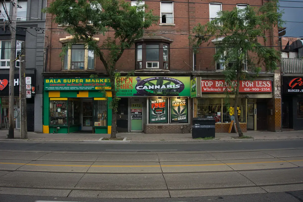 Storefronts on Queen Street West in Parkdale, with streetcar tracks running along the foreground