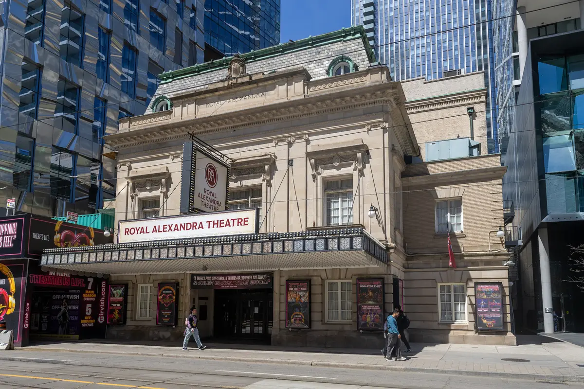 Front of the Royal Alexandra Theatre on King Street West, with its name on a sign above the entrance and show posters along the ground floor