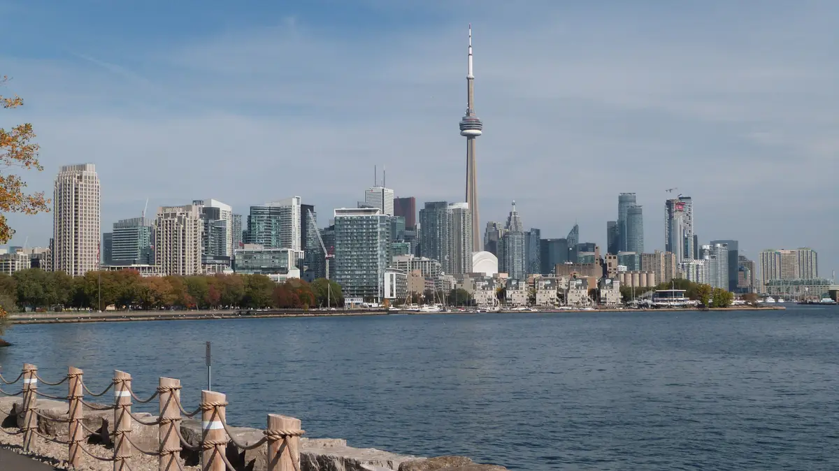 Toronto's skyline seen across open water, with the CN Tower in the middle and a rope railing in the foreground