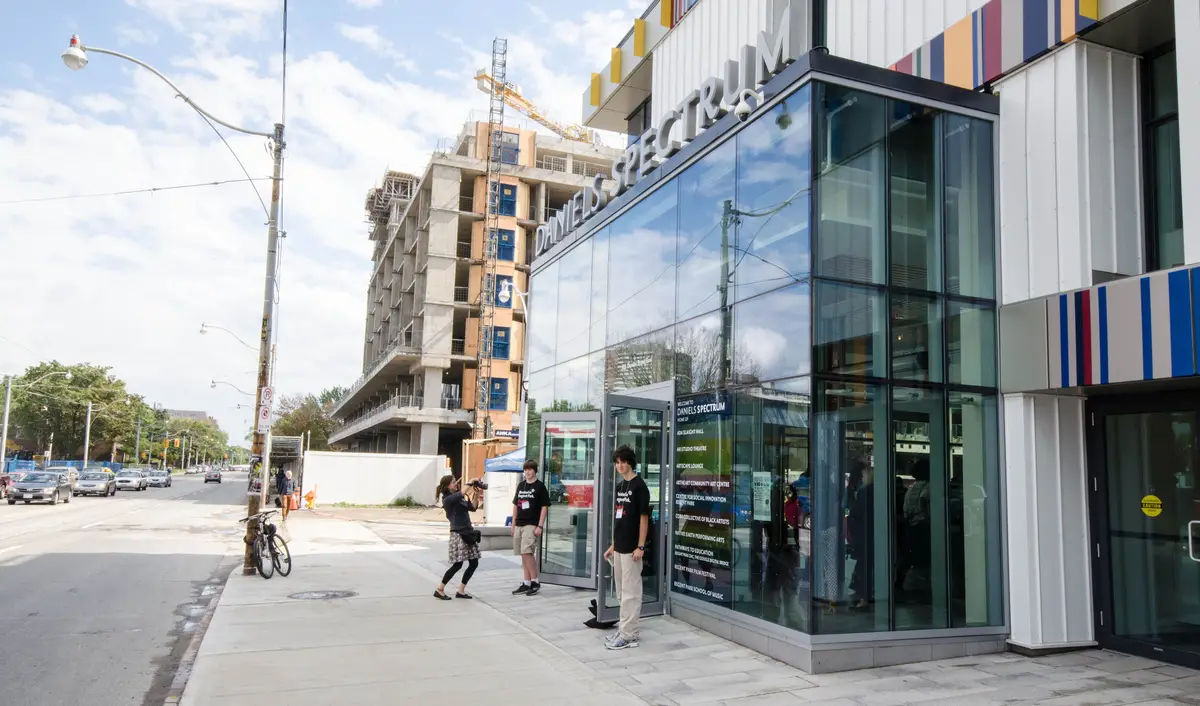 The glass entrance of Daniels Spectrum with its name on the wall above, and people at the doors