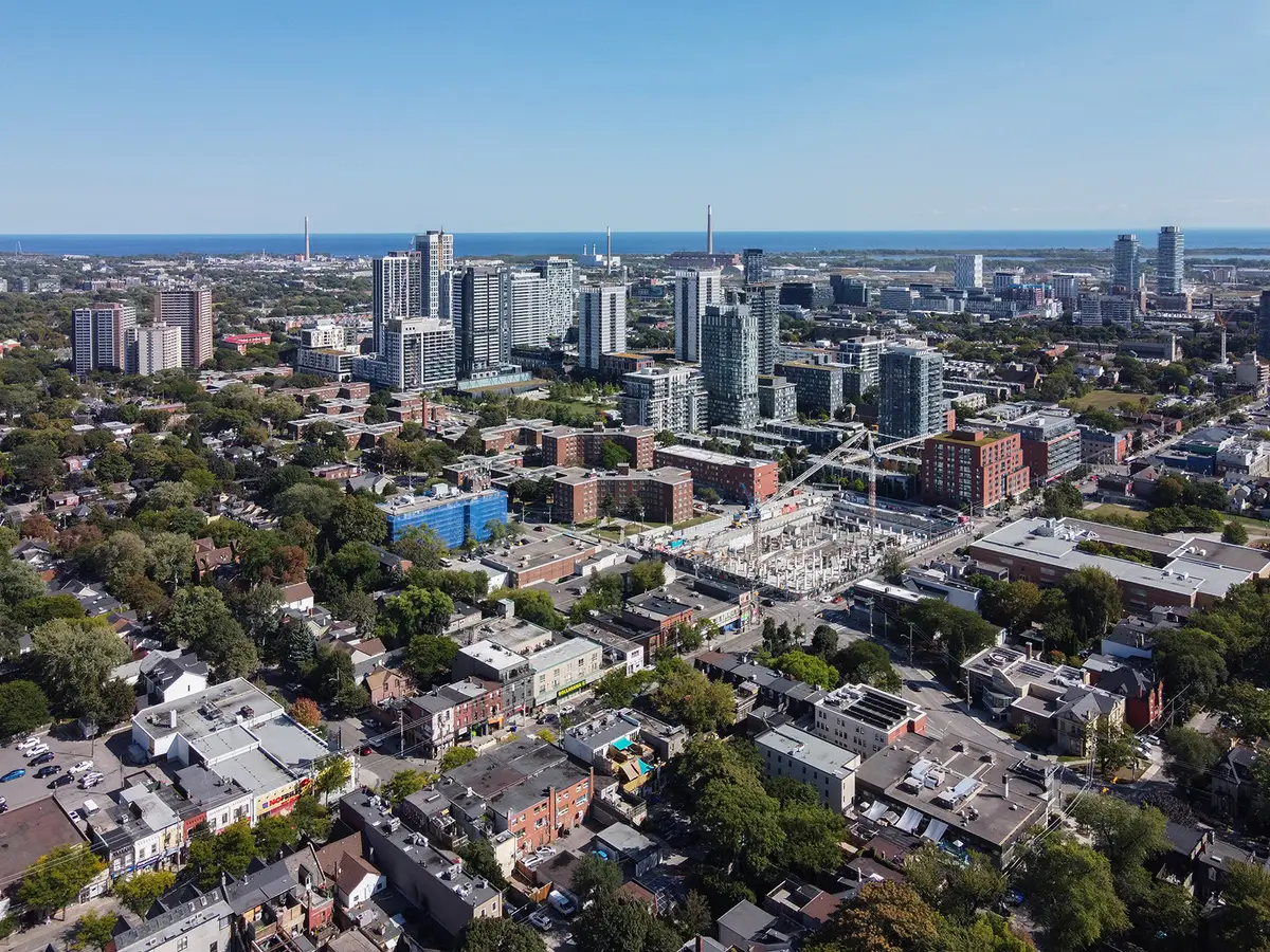 Aerial view of Regent Park's low-rise streets and tall towers, with open water on the horizon