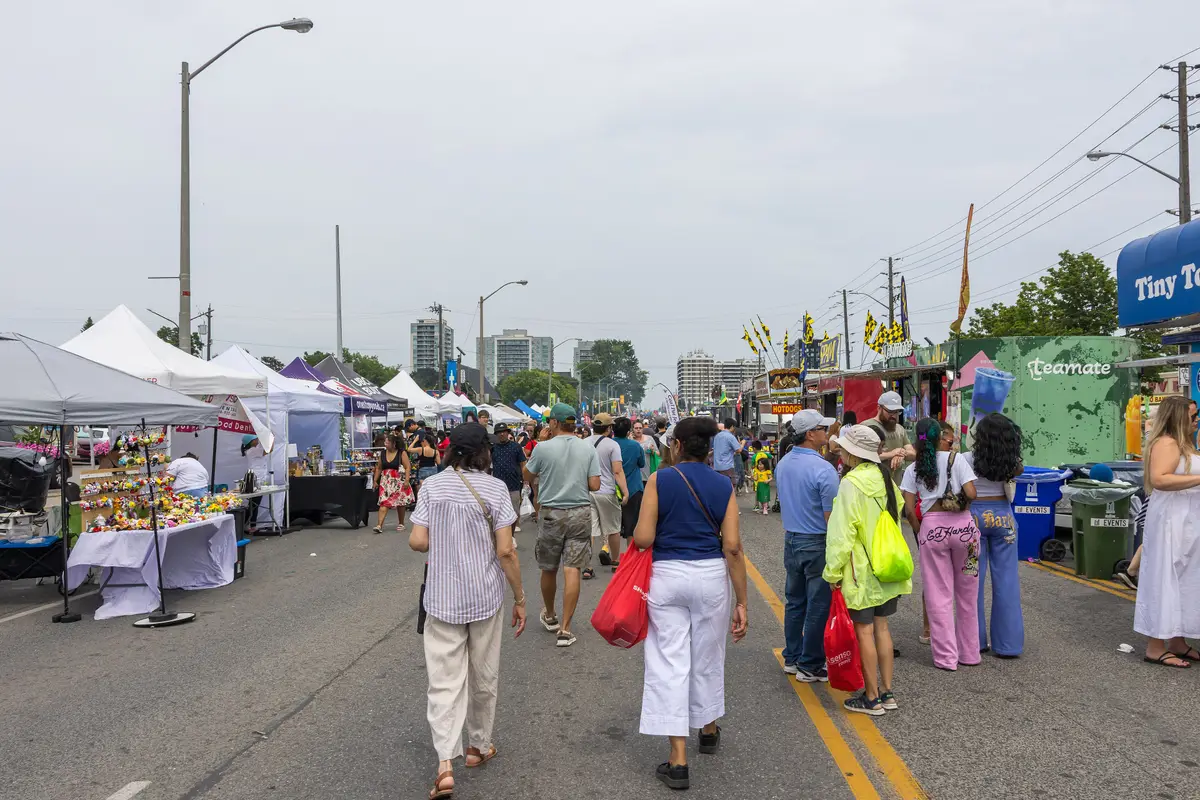 Vendor tables and tents along a closed stretch of Lawrence Avenue East with visitors walking past.