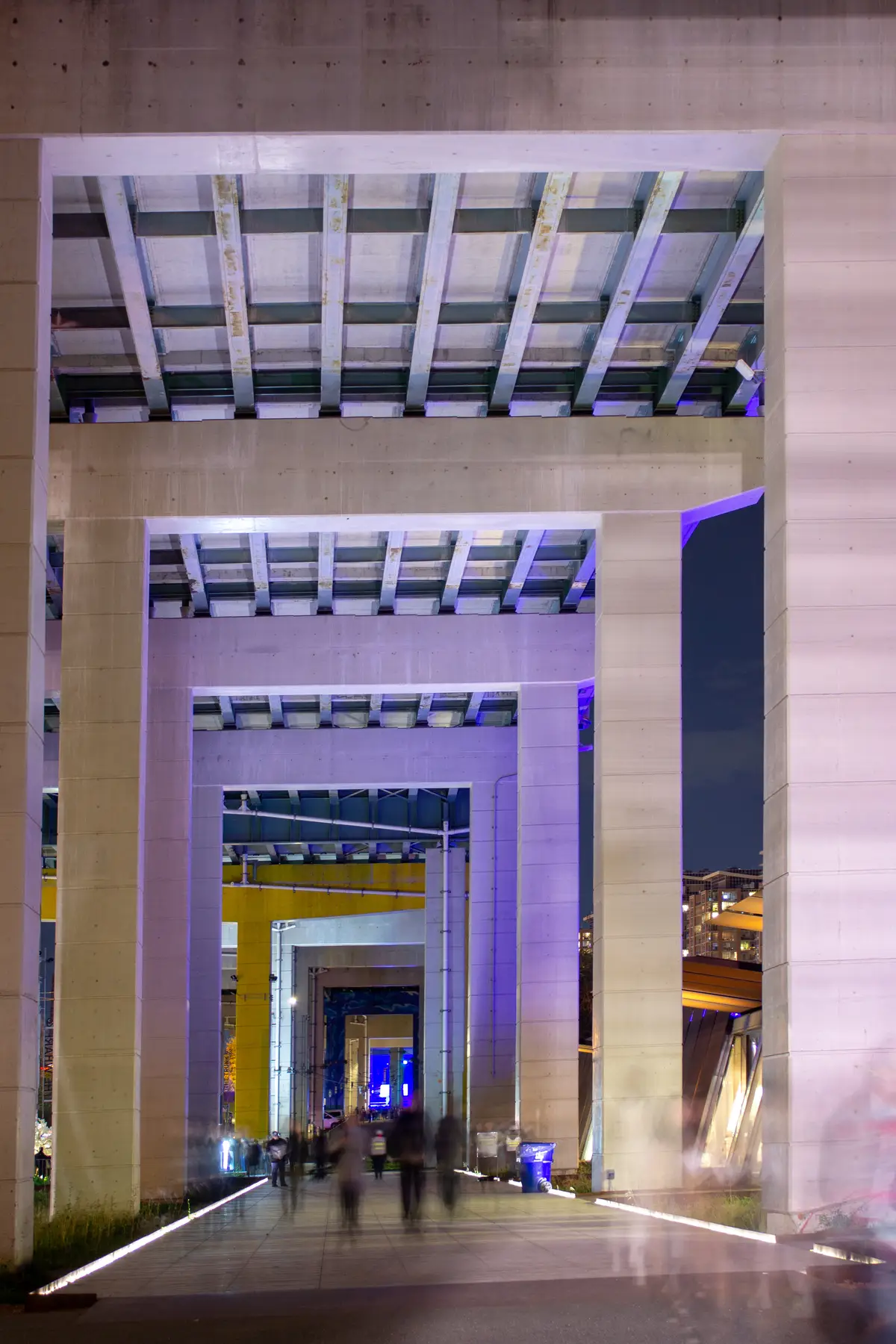 Lit concrete columns and passageways under the Gardiner Expressway at the Bentway, photographed at night during Nuit Blanche.