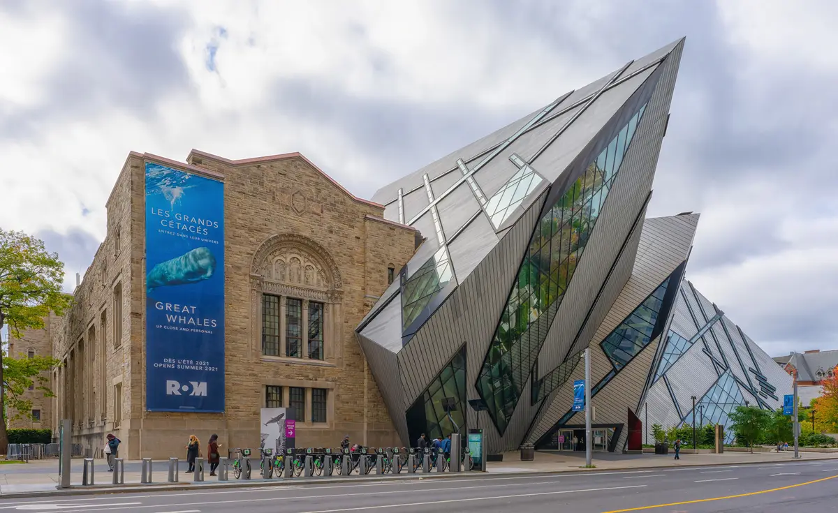 The Royal Ontario Museum: a sandstone building beside an angular glass-and-metal addition, with a whale banner on the front