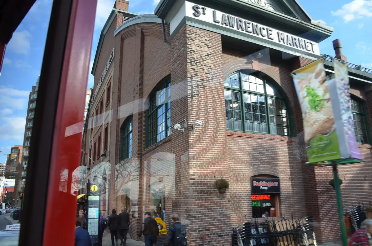 The red-brick corner of St. Lawrence Market with its name above an arched window, under a blue sky