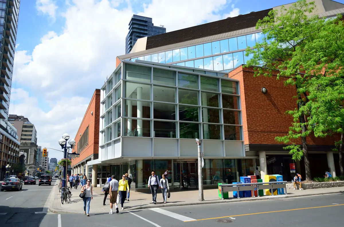 The glass-fronted corner of the Toronto Reference Library with people walking past on the sidewalk