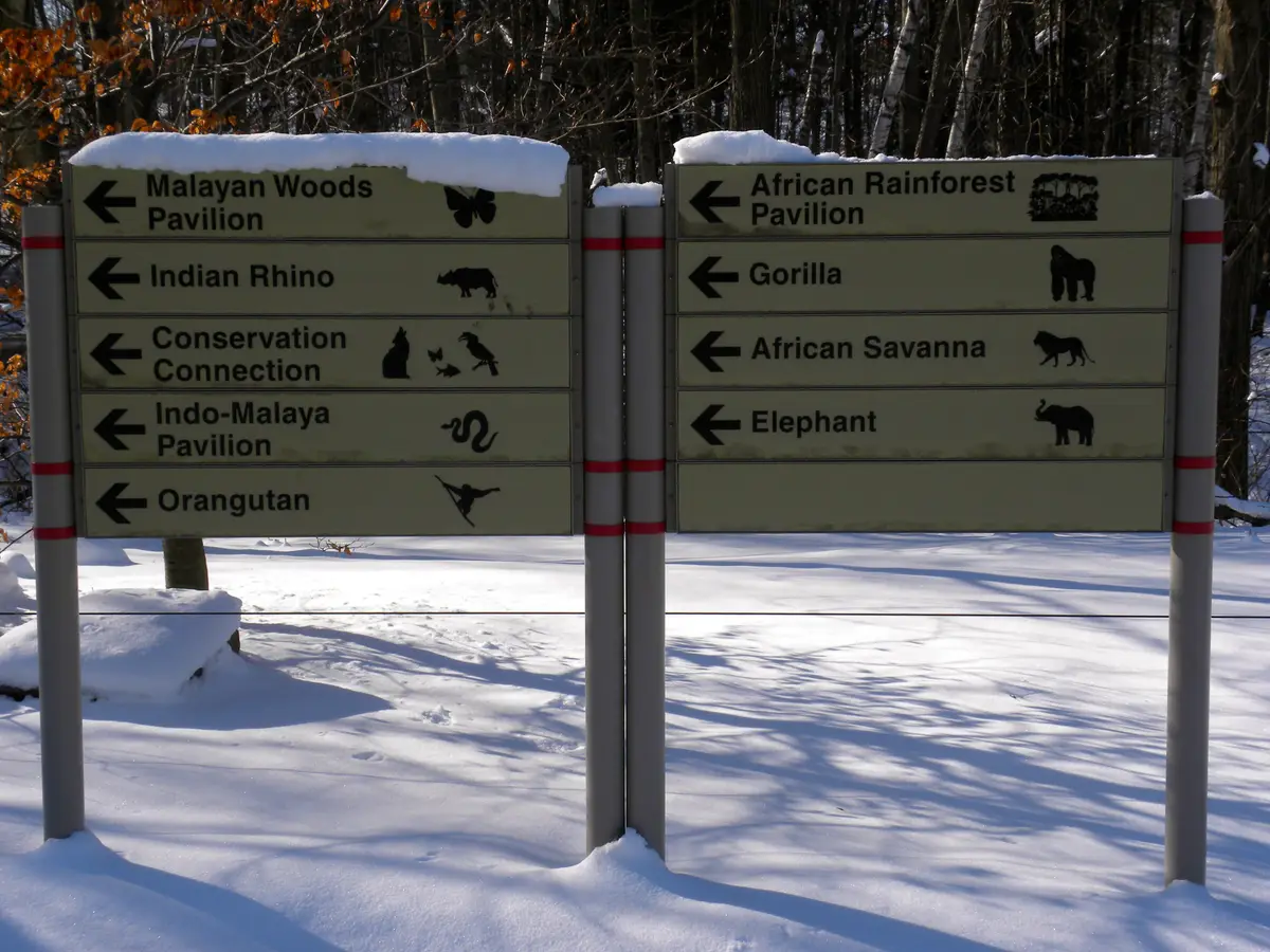Snow-dusted directional signs at the Toronto Zoo, pointing to pavilions and animal areas